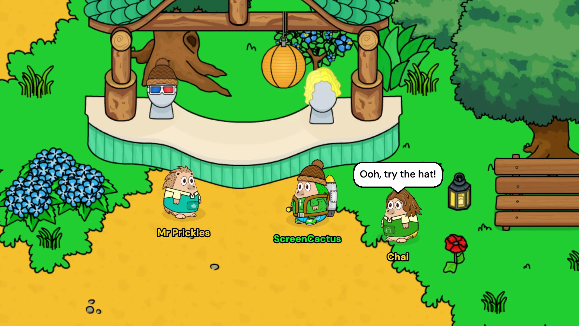 Mr Prickles at his clothes stall in the summer Village, with ScreenCactus browsing and Chai saying ooh, try the hat